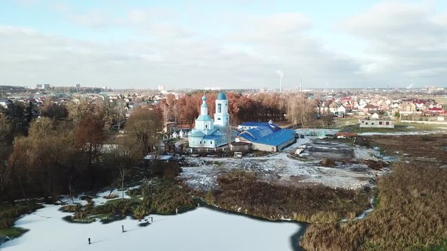 Beautiful orthodox church on the bank of the river Klyazma in the city of Noginsk. The picturesque surroundings with a dam on the river. Sunny autumn day.