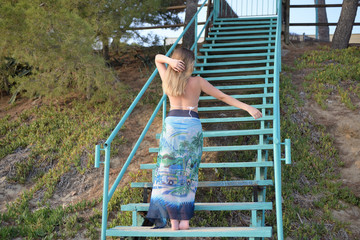 Fototapeta premium Blonde girl dances on stairs back to the camera and lowers her arms