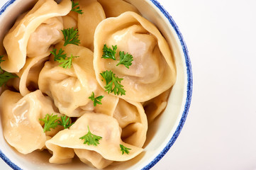 dumplings with parsley and onion at white wooden table top. Pelmeni - traditional russian cuisine...