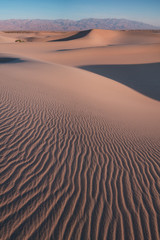 Early Morning Sunlight Over Sand Dunes And Mountains At Mesquite flat dunes, Death Valley National...
