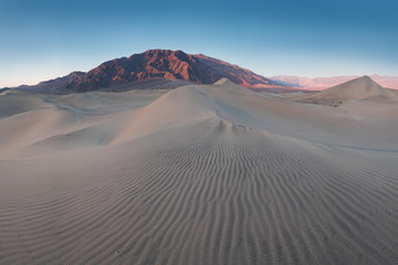 Fototapeta na wymiar Early Morning Sunlight Over Sand Dunes And Mountains At Mesquite flat dunes, Death Valley National Park, California USA Stovepipe Wells sand dunes, very nice structures in sand Beautiful background