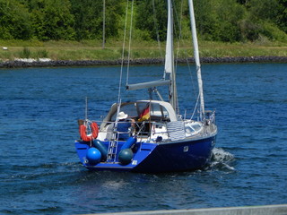 Obraz premium Skipper with sailing boat on a blue river, sailing trip on the Kiel Canal