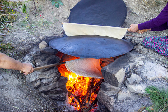 Traditional turkish  bread. Also known as "yufka ekmek" ,  natural organic homemade yufka bread. Woman cooking the handmade bread on wood fire.