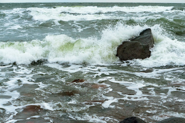 The waves crash on the rocks. Sea coast. Waves and storms at sea. Rocky shore.