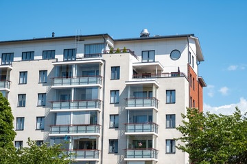 A bright multi-storey building with glazed balconies, trees grow on the balconies. Architecture of Finland.