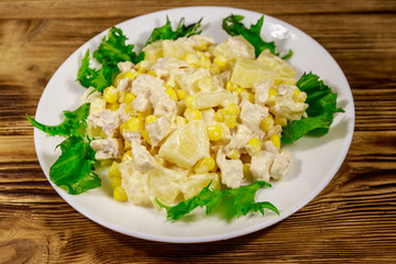 Festive salad with chicken breast, sweet corn, canned pineapple and mayonnaise on wooden table