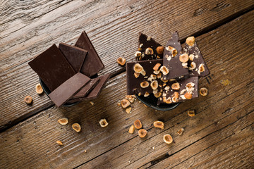 hazelnut dark chocolate pieces in black bowl on wooden table