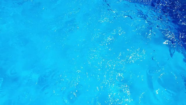 Solar glare on the water in the pool. Summertime, vacation, relaxing, holiday concept. Blue background.