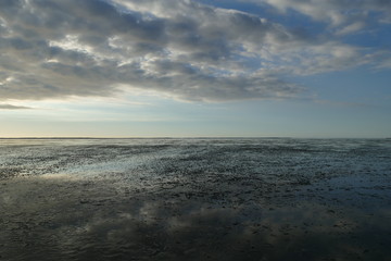 Early sunset on the North Sea directly on the beach. Orange/Blue sky and low tide.