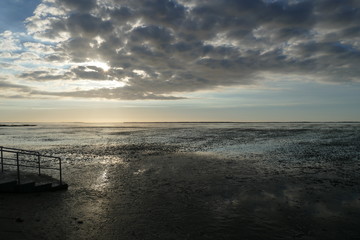 Early sunset on the North Sea directly on the beach. Orange/Blue sky and low tide.