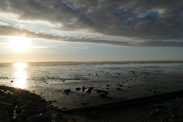 Early sunset on the North Sea directly on the beach. Orange/Blue sky and low tide.