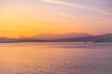 Fototapeta na wymiar Isle of Skye Sunrise - golden sun glow on ocean, mountains and islands