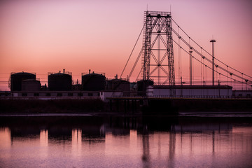 Silhouetted against the setting sun, the exterior of an oil refinery by the sea