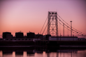 Silhouetted against the setting sun, the exterior of an oil refinery by the sea