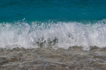 Sea water waves foam lapping to coastal shore