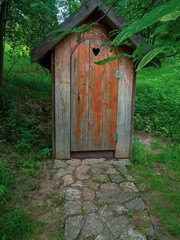 Wooden ecological composting toilet on countryside with a heart shape in the door