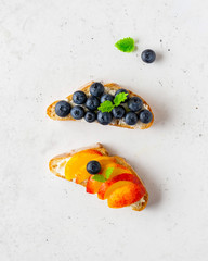 Various toasted bread with peach, blueberry, ricotta (cream cheese), mint.