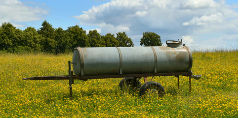 Water tank, field with yellow flowers, pasture.