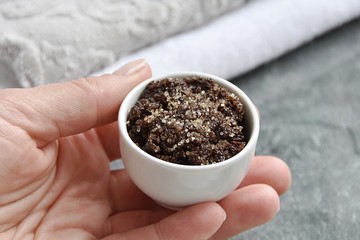 Woman hand holding small bowl with coffee, honey and brown sugar lip scrub.