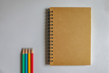 Multi-colored pencils and brown notebooks on a white background can be used to make backgrounds.