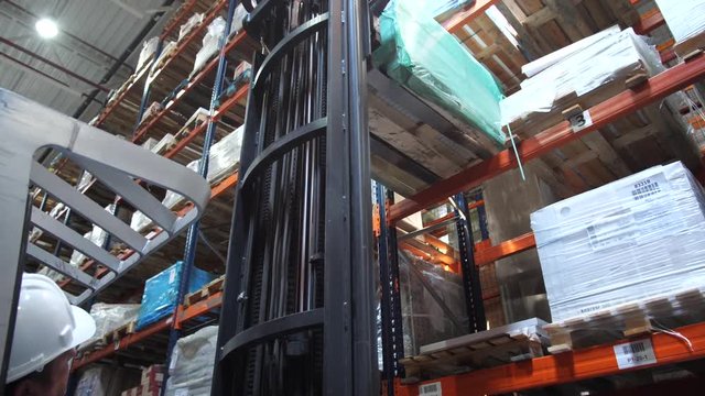 The driver on the forklift lifts the pallets with the box on the top shelf and leaves. 4K Slow Mo