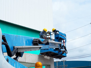 Construction worker at construction site using lifting boom machinery