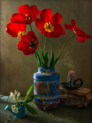 Still life with a bouquet of tulips extinguished candles and a watering can. Vintage. Retro.