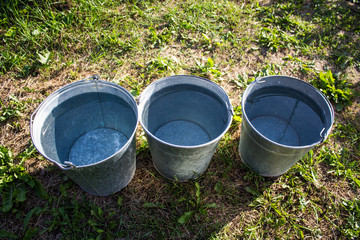 Three iron buckets of clean water on the grass © Inna