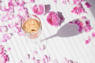 a glass of champagne and rose petals on a white background women's party