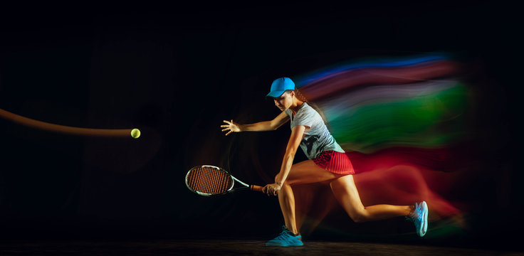 One caucasian woman playing tennis isolated on black background in mixed and stobe light. Fit young female player in motion or action during sport game. Concept of movement, sport, healthy lifestyle.