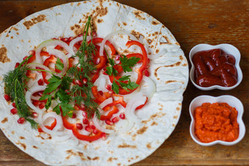 Red bell peppers, onions, pomegranate and parsley on lavash for roasted meat, sausages or sausages are served with ketchup and Armenian snack Aivar. The view from the top.
