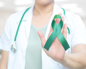 Gallbladder and Bile Duct Cancer Awareness Month concept. Kelly green ribbon awareness symbolic concept on doctor hand.