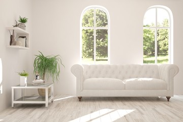 Stylish room in white color with sofa and summer landscape in window. Scandinavian interior design. 3D illustration