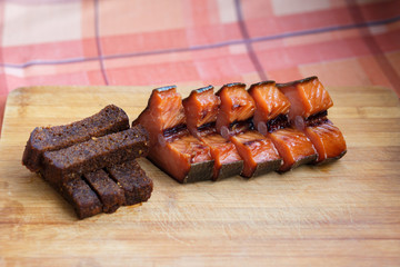 Beer snack. Fried black bread and red smoked fish. Black bread and smoked fish cut into pieces, lie on a wooden Board.