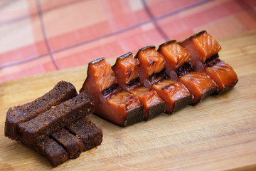 Beer snack. Fried black bread and red smoked fish. Black bread and smoked fish cut into pieces, lie on a wooden Board.