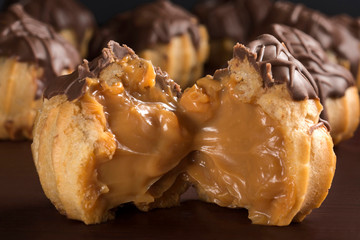 One open  traditional type of Brazilian profiterolis bakery candy called carolina in wood background