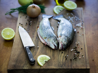 Raw trout on the table with a slice of lemon, salt and spices.
