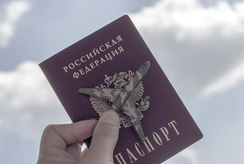 Travel concept, copy space. Airplane, passport  in female hand on blue sky background.