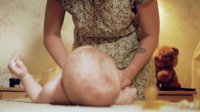 Mom changes the diaper baby. Beautiful white girl mother changes the diaper to her little child, the action takes place in the nursery