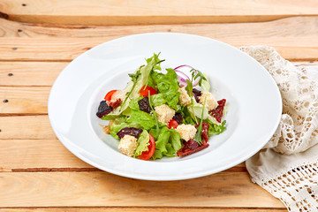 vegetarian salad with dried tomatoes and croutons on the wooden background