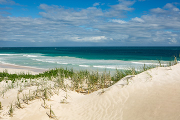 wide angle view of a white sandy beach with high dunes in Western Australia with big waves breaking on the beach