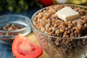 Buckwheat. Porridge with a piece of butter in a glass plate on a blue wooden table. breakfast, healthy food.
