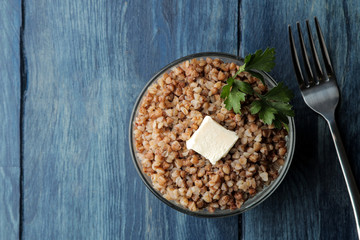 Buckwheat. Porridge with a piece of butter in a glass plate on a blue wooden table. breakfast, healthy food. top view