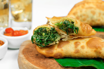 Traditional Brazilian fried pastry called pastel stuffed with Exotic edible plant called taioba with one open
