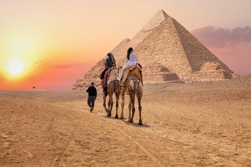 Tourists on camels near the Great Pyramids of Giza, Egypt - obrazy, fototapety, plakaty