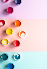 Multicolor gouache on a colorful background in pastel colors. Paint in containers, top view, copy space.