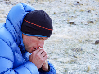 close up of a concentrated and pensive mountain climber in thick down jacket lost in thought