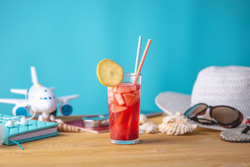 Glass of red lemonade drink with lemon and fruit and straw on the table. Concept of summer Sunny vacation at the resort