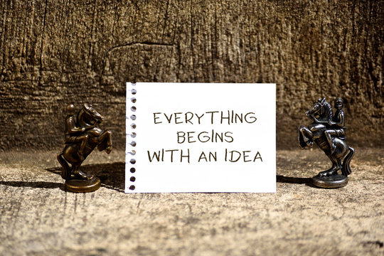 Conceptual hand writing showing Everything Begins With An Idea. Concept meaning steps you take to turn an idea into a reality Two Bronze Chessmen Knights Ring Notepad Sheet Folded Half