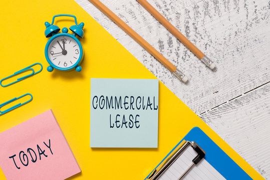 Word writing text Commercial Lease. Business photo showcasing refers to buildings or land intended to generate a profit Notepads clips paper sheet clipboard markers alarm clock wooden background